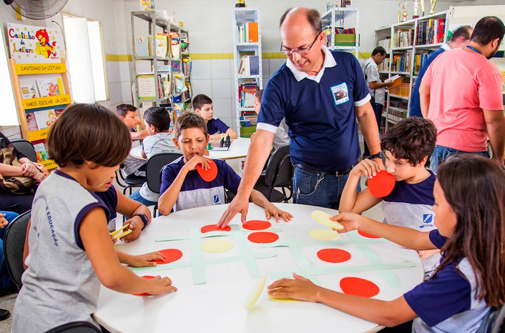Alunos e professor jogam “jogo da velha” com círculos feitos com papel colorido.