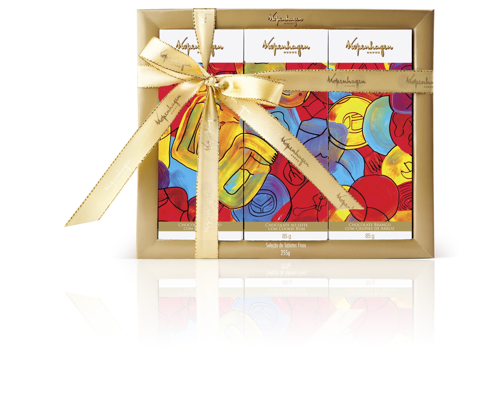 Caixa de embalagem quadrada com borda dourada e a inscrição “Kopenhagen” contendo três tabletes de chocolate em embalagens estampadas com obra de arte abstrata e colorida. A caixa está envolta por fita dourada e um grande laço.