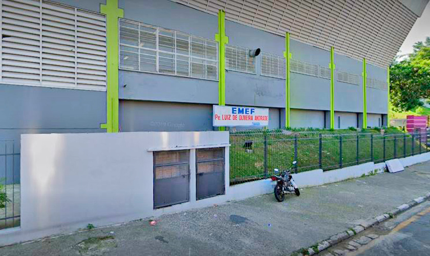 Fachada da escola municipal Padre Luiz de Oliveira Andrade, em Barueri. A escola possui muros muros externos brancos, enquanto os internos são azuis, e portões em azul escuro. Fim da descrição.
